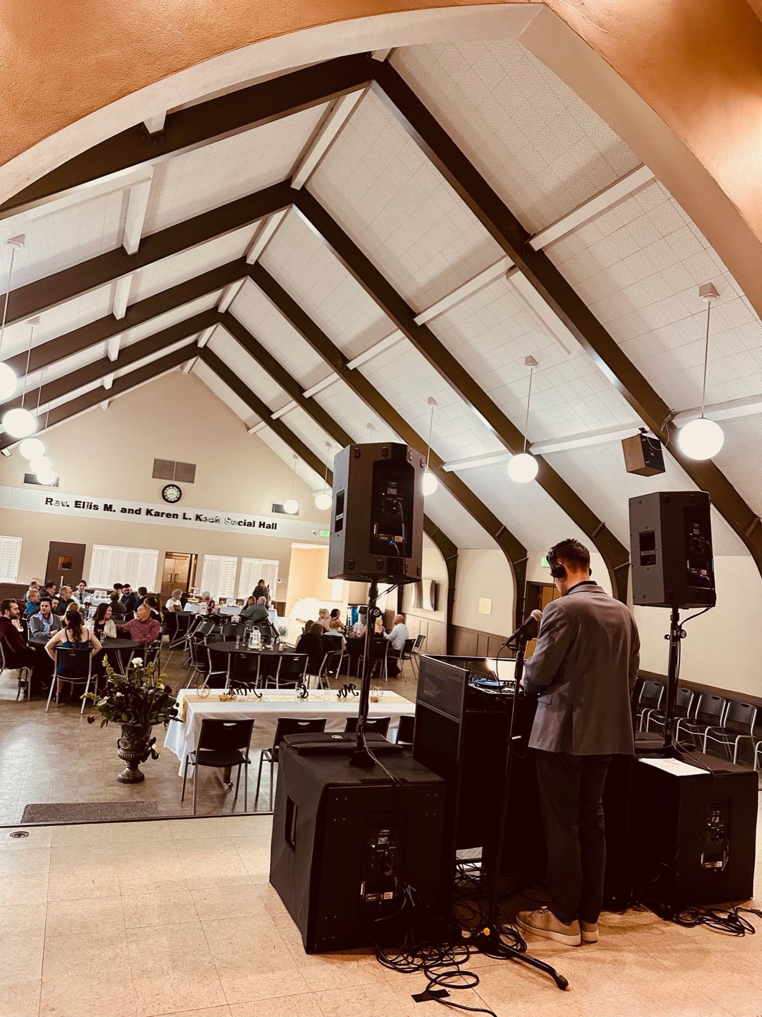 DJ coverage in a large social hall with guests seated for a wedding reception